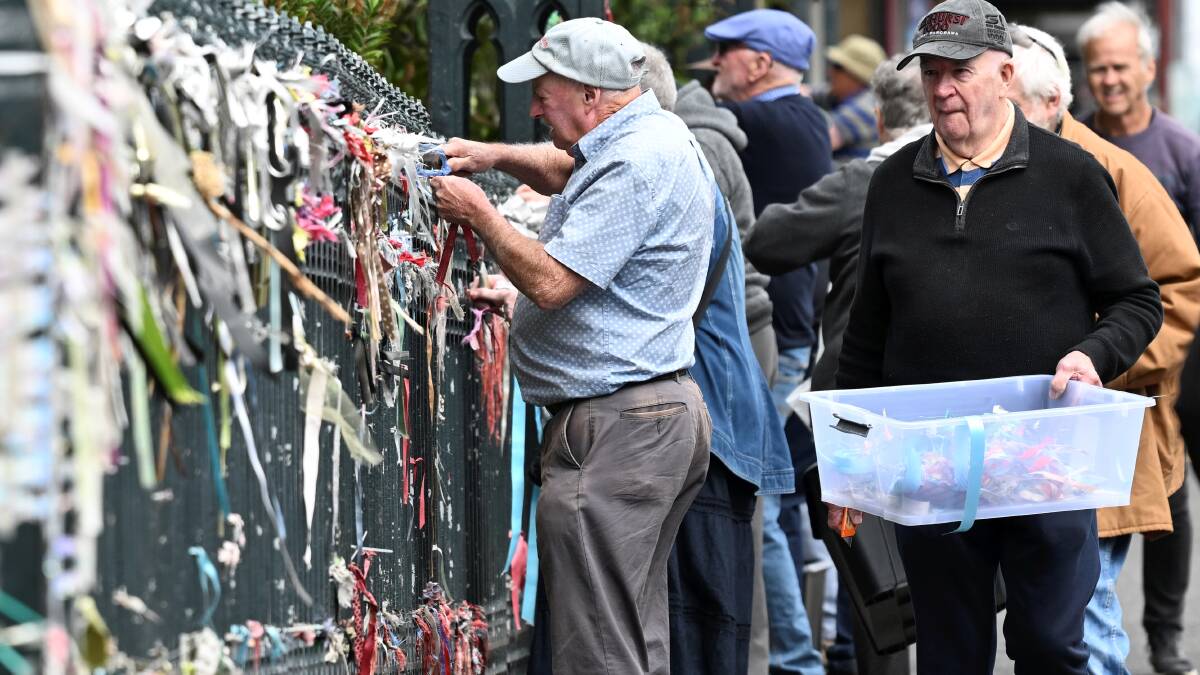 Parishioners remove ribbons from St Patrick's Cathedral's fence. Picture by Lachlan Bence