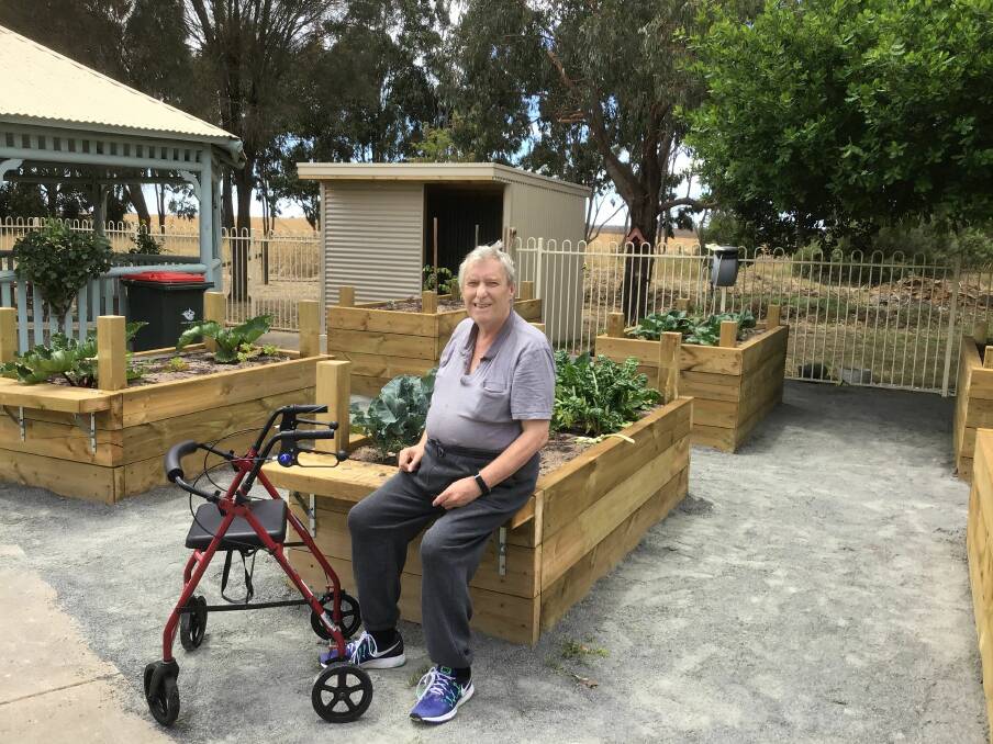 ADMIRING: Parkland House Hostel resident Garry Moloney checking out the plantings in the raised garden beds.Picture: Contributed. 