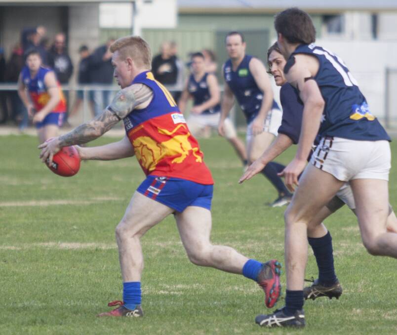 IN THE CLEAR: Great Western Lion Chris Bourke breaks away from Ararat Eagles players in order to get his kick away. Picture: PETER PICKERING
