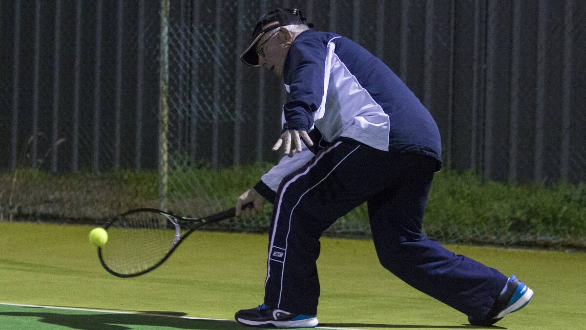 Tough shot: John Hannett reaching low to scoop the ball at the Ararat City Tennis Club on Wednesday night was one of the members who returned to play on the courts after they were washed out last week. Picture: Peter Pickering. 
