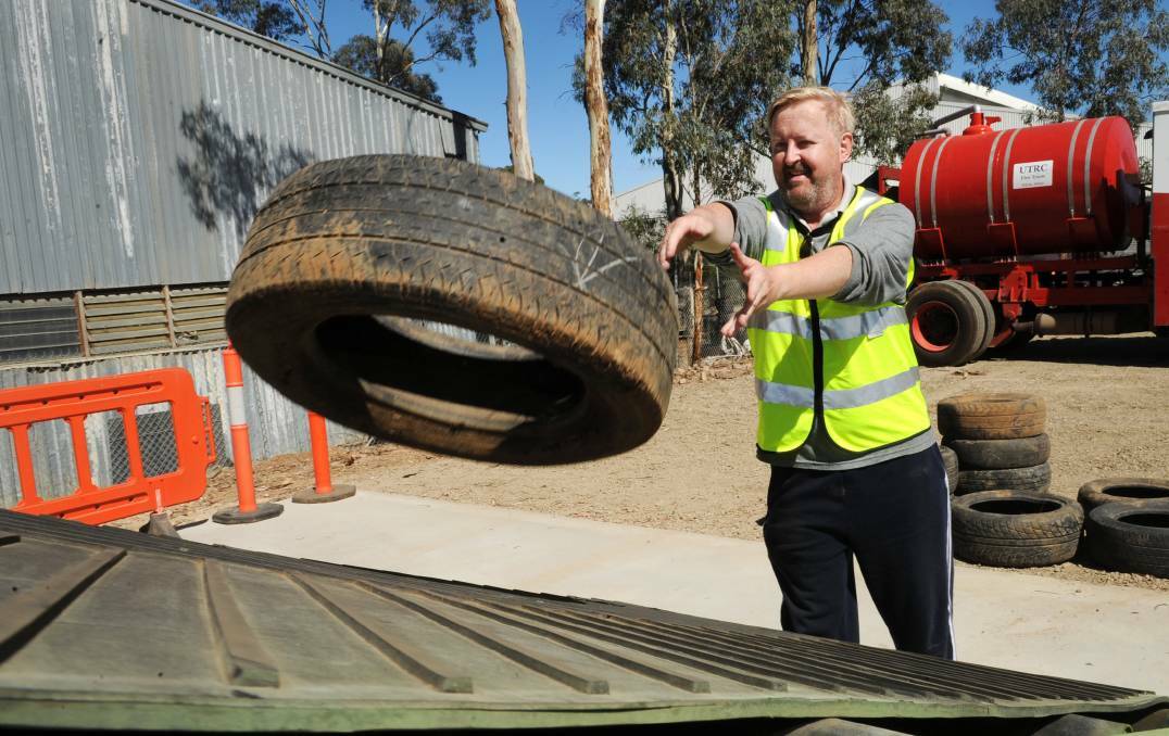 SHREDDING: Used Tyre Recycling Corporation chief executive Matthew Starr throws a tyre on a shredding machine. Photo: Paul Carracher