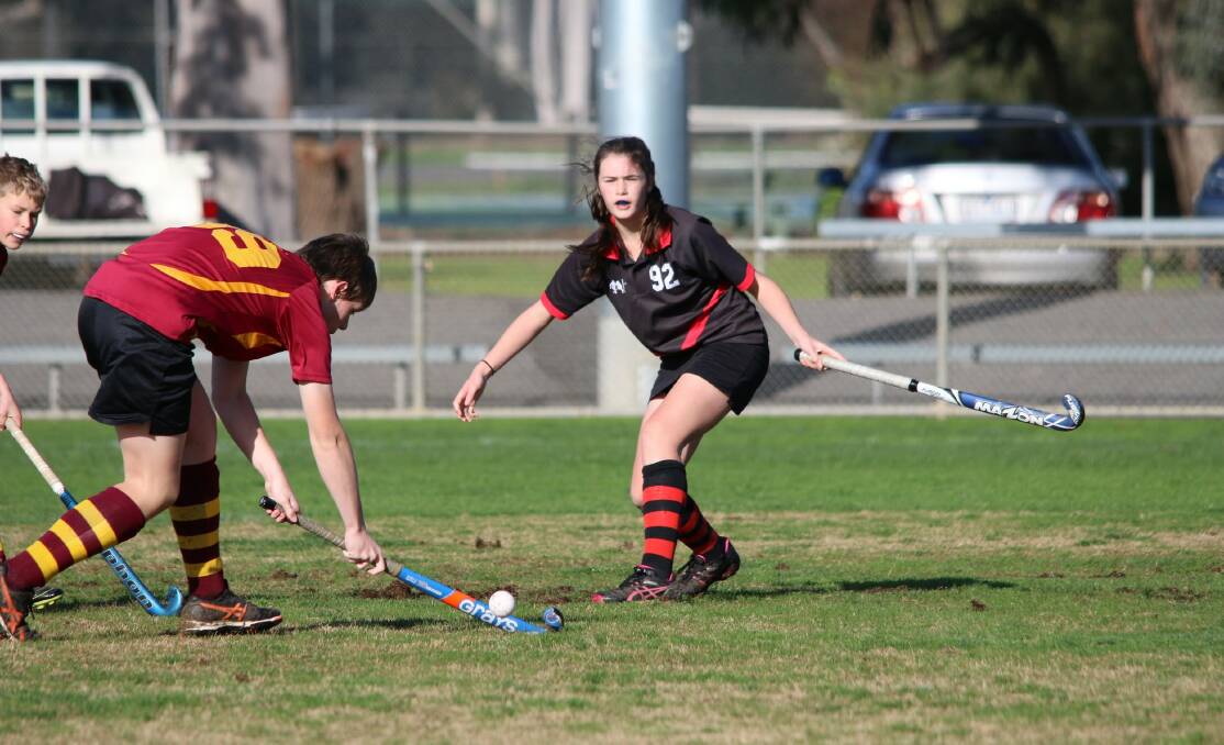 ROUND 12: Horsham Bombers’ Kira Guest clears the ball past her Warracknabeal opponent Lachie Hicks in the Wimmera Hockey Association. Picture: CONTRIBUTED