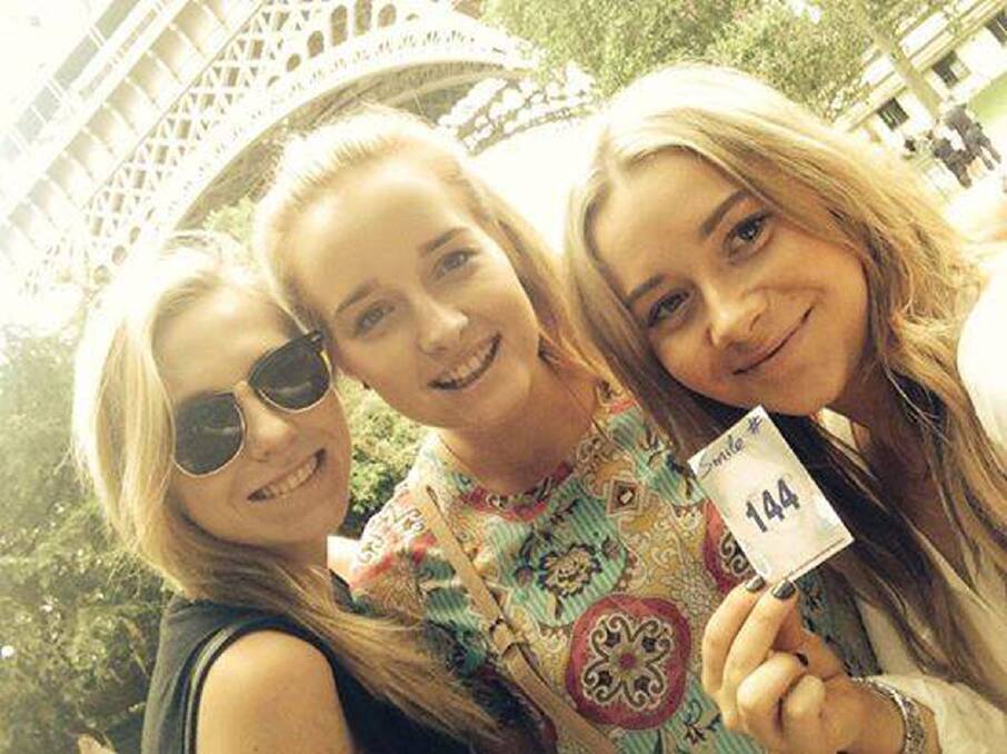 Elyssa Hart (centre) and Ellie Price (right) at the Eiffel Tower with smile card number 144.