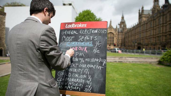 A bookmaker writes the latest odds on the result of the upcoming UK general election outside the Houses of Parliament in central London on May 6, 2015.  Photo: Leon Meal