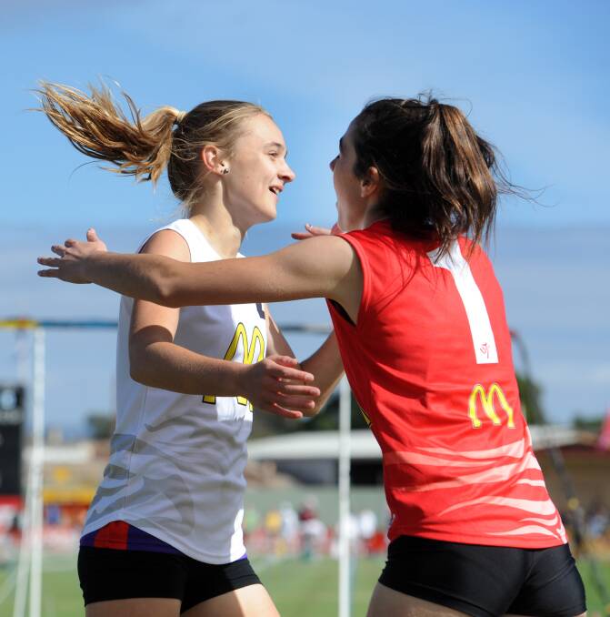 Remi Kuhne, Dimboola, and Anna Bush, Horsham, hug after a heat of the Little Athletics 100m handicap at Sunday's Stawell Gift family day.