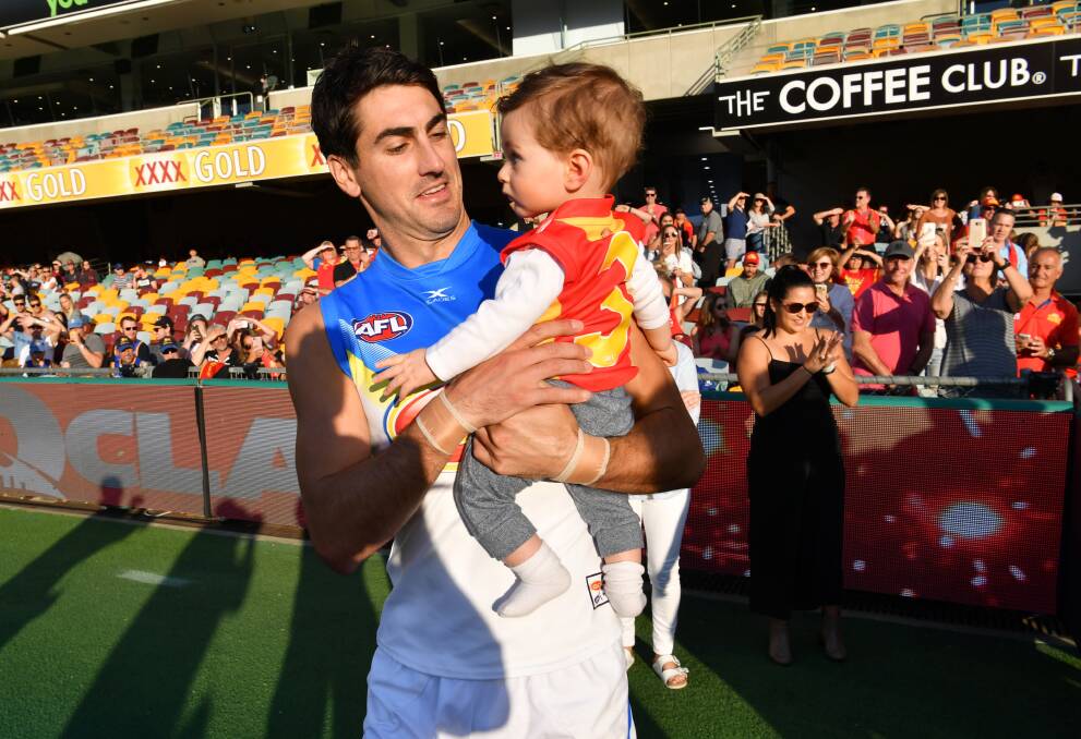 BIG DAY: Matt Rosa carries his son Otis onto the ground before playing his 200th AFL game on Saturday. Picture: AAP IMAGE