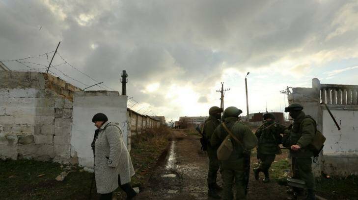 Gloom: A woman passes unidentified Russian soldiers at the Ukrainian base in Perevalnoye. Photo: Kate Geraghty
