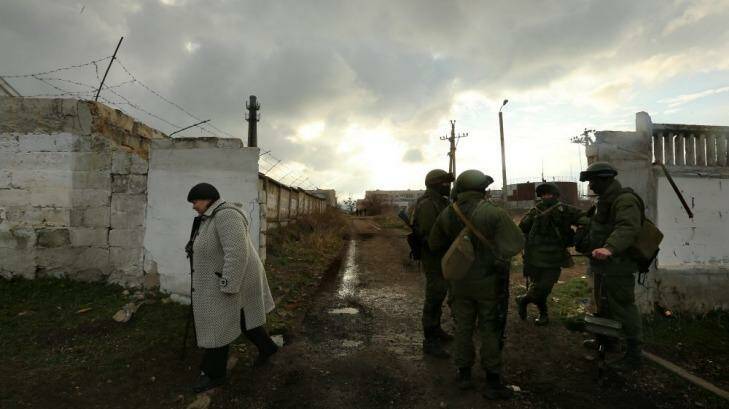Gloom: A woman passes unidentified Russian soldiers at the Ukrainian base in Perevalnoye. Photo: Kate Geraghty