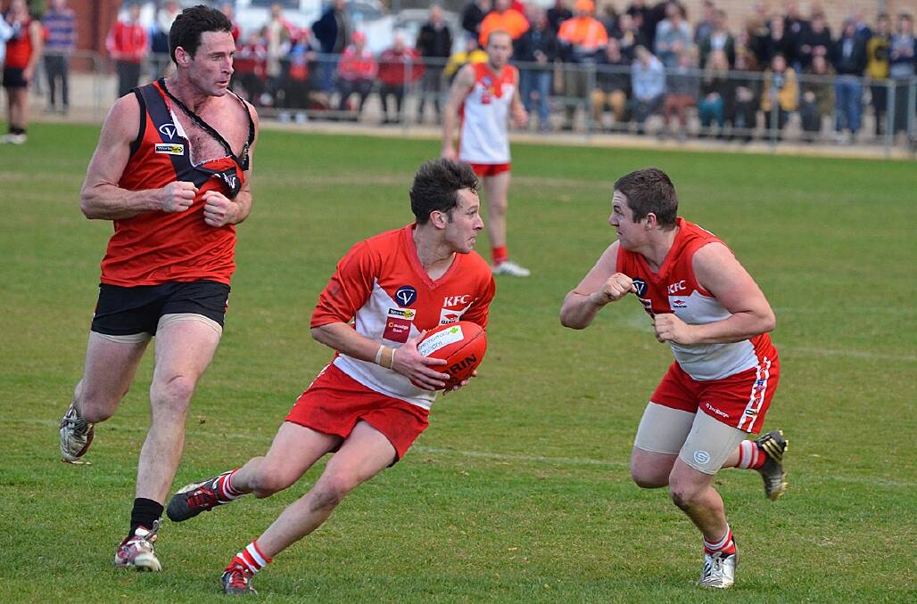 Ararat Rats’ joint-captain Alan Batchelor gathers the ball as team mate Jake Williamson looks to lay a shepherd on Stawell ruckman Shane Field.