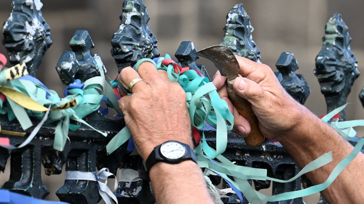 Loud Fence ribbons are removed from St Patrick's Cathedral fence. Pictures by Lachlan Bence
