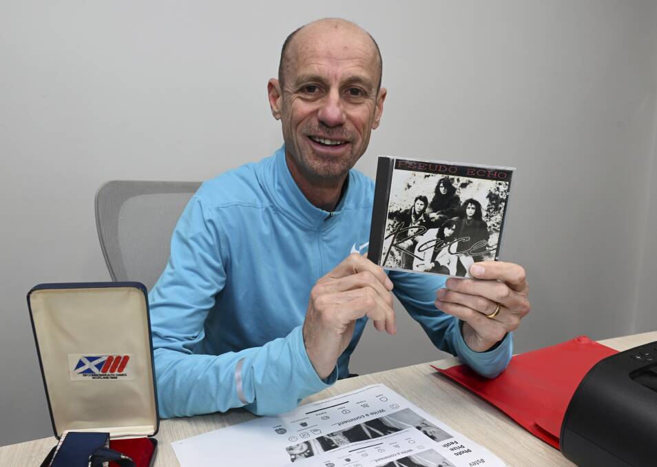 Steve Moneghetti at the big reveal with his 1986 marathon medal and the Pseudo Echo album with the song he inspired: Take on the World. Picture by Lachlan Bence.