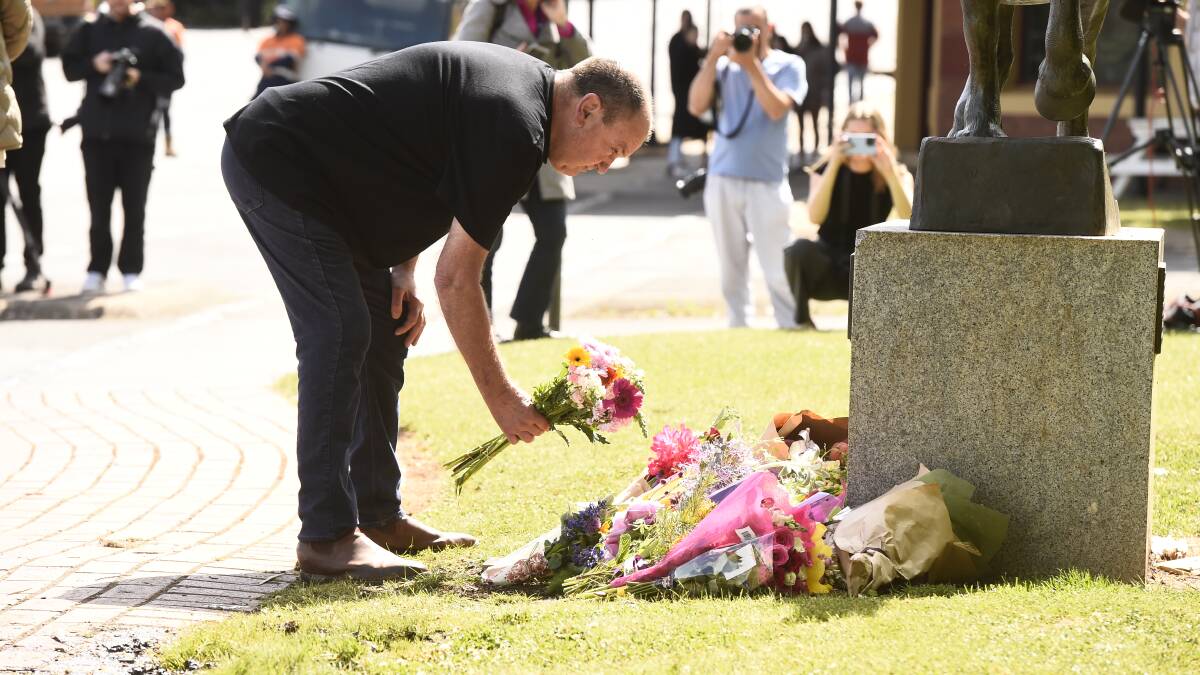 A man lays flowers at the foot of the statue in the grassy area outside the Royal Hotel in Daylesford. Picture by Adam Trafford. 
