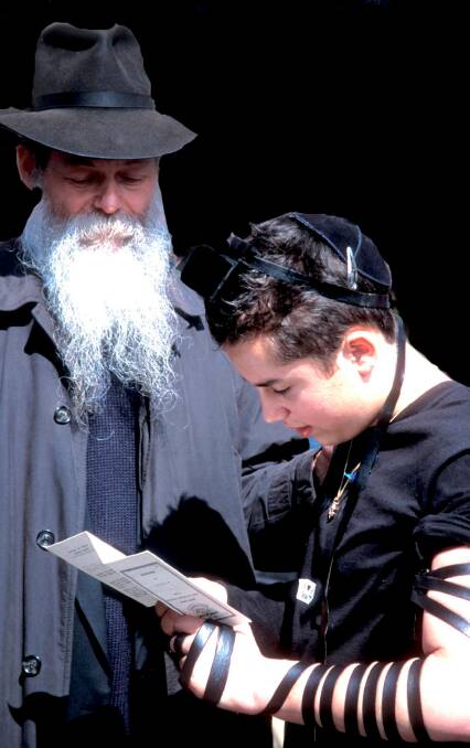 Jewish elder instructs a boy on the significance of the tefilin bindings Photo by Paul Gapper