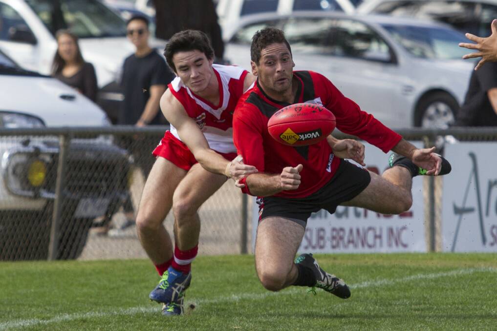 CONTEST: Stawell's Damian Joiner disposes of the ball under heavy pressure from an Ararat opponent on Friday. Picture: Peter Pickering