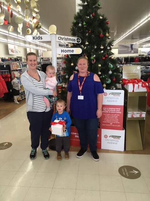 Target team member Sharlmaine McColl with Sarah Tyler holding Zoe and Ted by the Christmas tree.