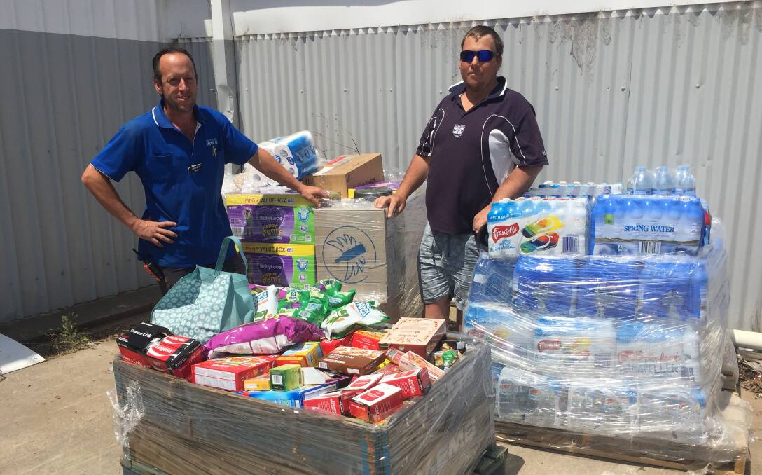 Mitre 10 Ararat store manager Mark Sullivan with Brodie Hunter and some of the pallets of donated items. 