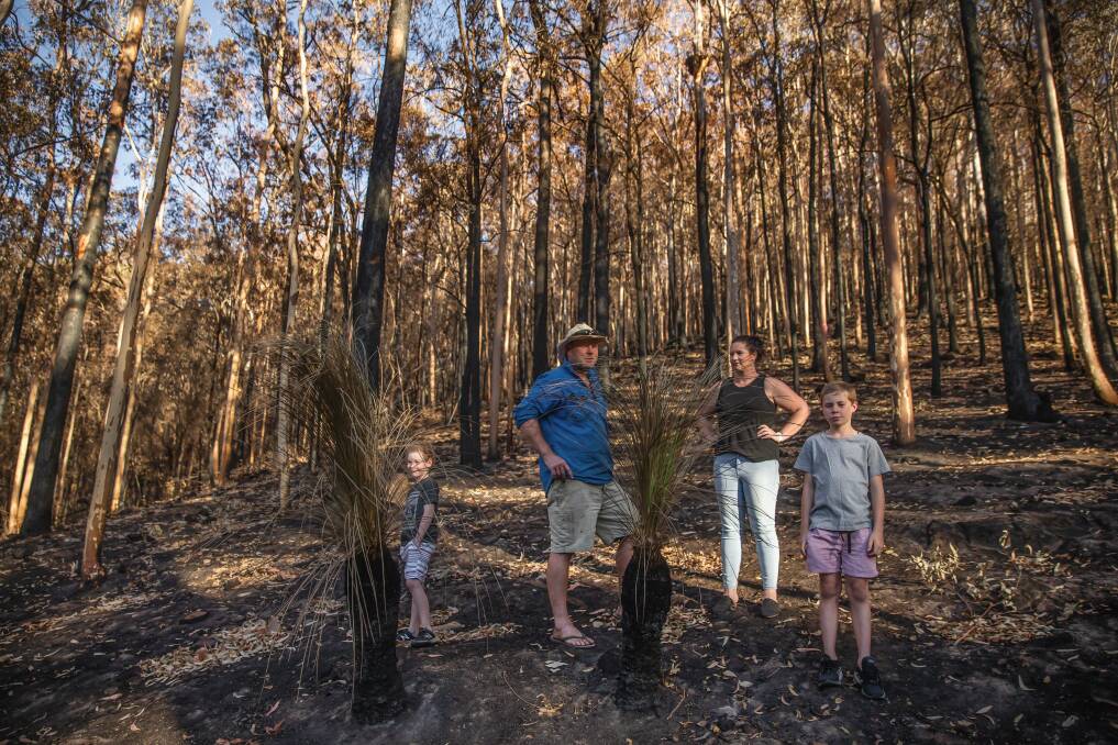FORTUNATE: Joel and Leah Eddy, with their sons, Hudson and Tom, inspect the burnt bushland behind their Martinsville house. Picture: Marina Neil