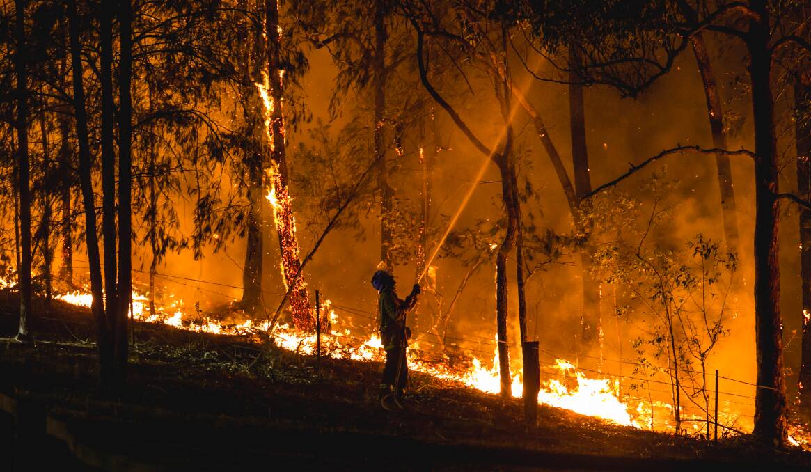 A NSW Rural Fire Service member fights the flames at Martinsville. Picture: Marina Neil