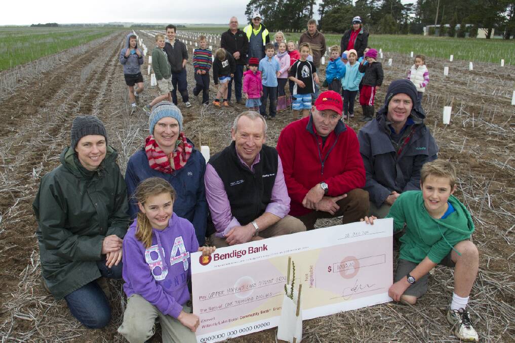 Briody and Archie hold the cheque for Jane Drum, Celia Tucker, Branch Manager of the Lake Bolac-Willaura Community Bank Trevor Link, David Carter from the Tatyoon Recreation Reserve and Craig Drum while the rest of the planting crew look on.