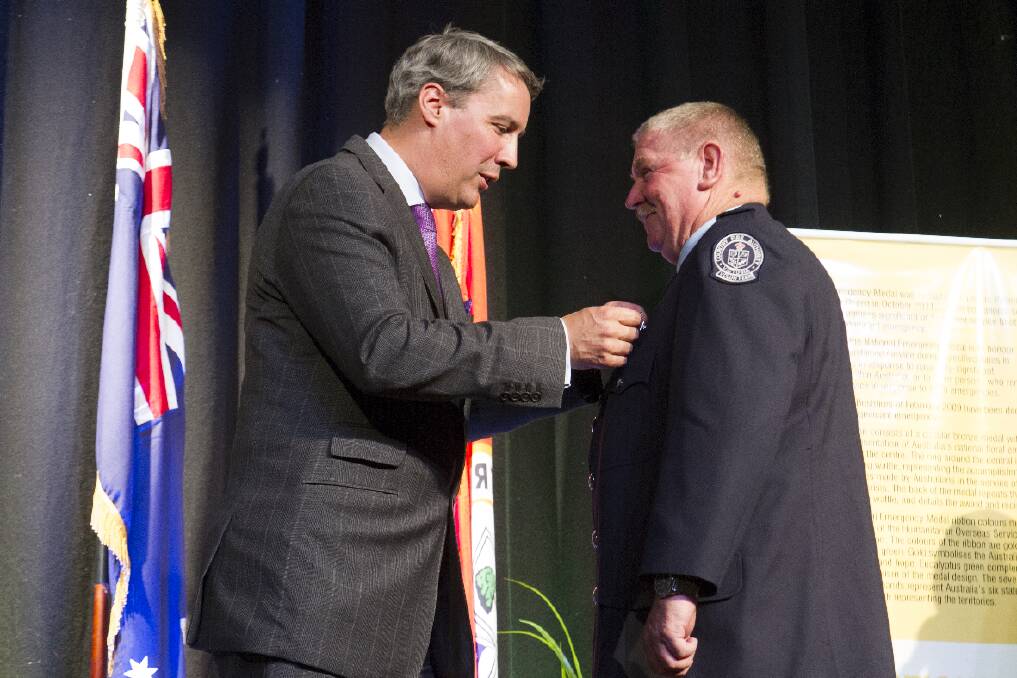 Wayne Wilde receives his medal from Commissioner Michael Hallowes for his work during the Black Saturday fires.
